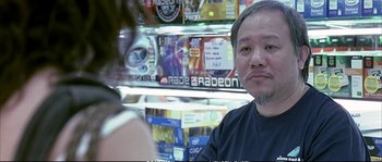 Movie still from “Boarding Gate” (2007), directed by Olivier Assayas – A man sitting in front of a display of video games; Close Up shot, Over the shoulder angle