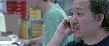Movie still from “Boarding Gate” (2007), directed by Olivier Assayas – A man is talking on a cell phone; Close Up shot, Low angle