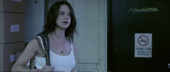 Movie still from “Boarding Gate” (2007), directed by Olivier Assayas – A woman with long dark brown hair wearing a white tank top; Close Up shot, Low angle