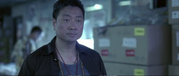 Movie still from “Boarding Gate” (2007), directed by Olivier Assayas – A man in a black jacket is looking at the camera; Close Up shot, Low angle