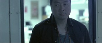 Movie still from “Boarding Gate” (2007), directed by Olivier Assayas – A person wearing a black jacket; Close Up shot, Low angle