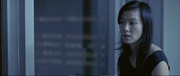 Movie still from “Boarding Gate” (2007), directed by Olivier Assayas – A woman standing in front of a glass window; Close Up shot, Over the shoulder angle