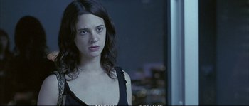 Movie still from “Boarding Gate” (2007), directed by Olivier Assayas – A woman with long dark hair is looking at the camera; Close Up shot, Over the shoulder angle