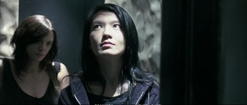 Movie still from “Boarding Gate” (2007), directed by Olivier Assayas – A woman with long black hair looking upward; Close Up shot, Low angle