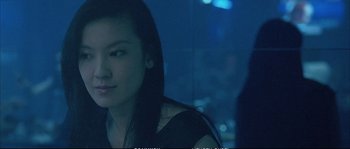 Movie still from “Boarding Gate” (2007), directed by Olivier Assayas – A young woman sitting in front of a window at night; Close Up shot, Over the shoulder angle