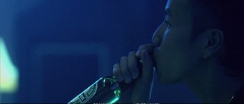 Movie still from “Boarding Gate” (2007), directed by Olivier Assayas – A person holding a bottle of beer in their hand; Close Up shot, Low angle