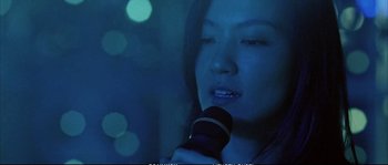 Movie still from “Boarding Gate” (2007), directed by Olivier Assayas – A woman holding a microphone in front of a window; Close Up shot, Low angle