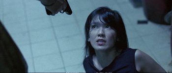 Movie still from “Boarding Gate” (2007), directed by Olivier Assayas – A woman holding a gun up to her face; Close Up shot, Over the shoulder angle