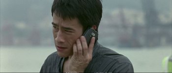 Movie still from “Boarding Gate” (2007), directed by Olivier Assayas – A man holding a cell phone up to his ear; Close Up shot, High angle