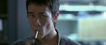 Movie still from “Boarding Gate” (2007), directed by Olivier Assayas – A young man is smoking a cigarette in the dark; Close Up shot, Low angle