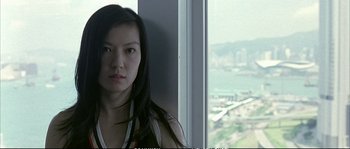 Movie still from “Boarding Gate” (2007), directed by Olivier Assayas – A woman standing in front of a large window; Close Up shot, Low angle