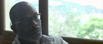 Movie still from “Boarding Gate” (2007), directed by Olivier Assayas – A person wearing glasses near a window; Close Up shot, Over the shoulder angle