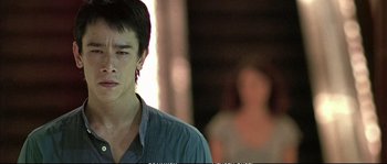 Movie still from “Boarding Gate” (2007), directed by Olivier Assayas – A man in a blue shirt is looking at the camera; Close Up shot, Low angle