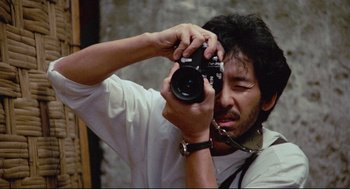 Movie still from “Boat People” (1982), directed by Ann Hui – A man taking a picture with a camera; Extreme Close Up shot, Low angle