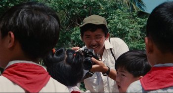 Movie still from “Boat People” (1982), directed by Ann Hui – A man taking a picture of a group of people; Extreme Close Up shot, Over the shoulder angle