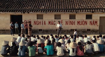 Movie still from “Boat People” (1982), directed by Ann Hui – A group of people sitting in front of a building; Extreme Wide shot, High angle