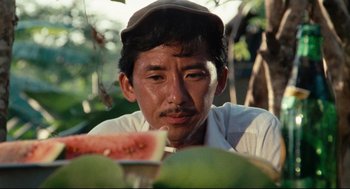 Movie still from “Boat People” (1982), directed by Ann Hui – A man sitting in front of a slice of watermelon; Close Up shot, Over the shoulder angle