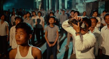 Movie still from “Boat People” (1982), directed by Ann Hui – A man taking a picture of a group of people; Medium shot, High angle