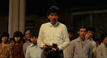 Movie still from “Boat People” (1982), directed by Ann Hui – A group of men standing in front of each other; Medium shot, Low angle