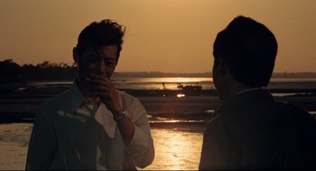 Movie still from “Boat People” (1982), directed by Ann Hui – Two men standing on the beach at sunset; Medium shot, Over the shoulder angle