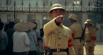 Movie still from “Boat People” (1982), directed by Ann Hui – A man in a tan uniform pointing to the side; Medium shot, Over the shoulder angle