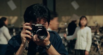 Movie still from “Boat People” (1982), directed by Ann Hui – A man taking a picture with a camera; Extreme Close Up shot, Low angle