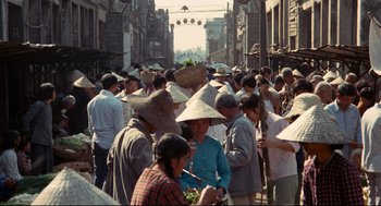 Movie still from “Boat People” (1982), directed by Ann Hui – A group of people walking down a street with hats on their heads; Wide shot, High angle
