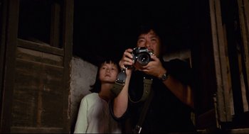 Movie still from “Boat People” (1982), directed by Ann Hui – A man and a woman taking a picture with a digital camera; Medium shot, Low angle
