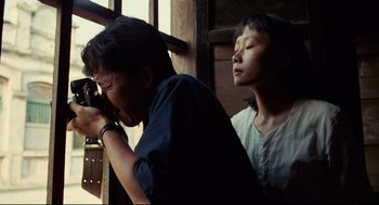 Movie still from “Boat People” (1982), directed by Ann Hui – A man and a woman looking at something in a mirror; Close Up shot, Over the shoulder angle