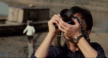 Movie still from “Boat People” (1982), directed by Ann Hui – A man taking a picture with a camera; Close Up shot, Over the shoulder angle