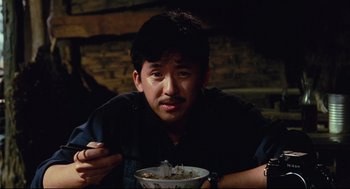 Movie still from “Boat People” (1982), directed by Ann Hui – A man sitting in front of a bowl of food; Close Up shot, Low angle