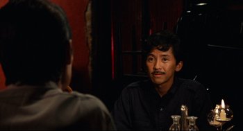 Movie still from “Boat People” (1982), directed by Ann Hui – A man sitting in front of another man in front of a mirror; Medium shot, Over the shoulder angle