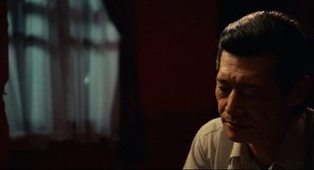 Movie still from “Boat People” (1982), directed by Ann Hui – An older man sitting in front of a window; Close Up shot, Over the shoulder angle