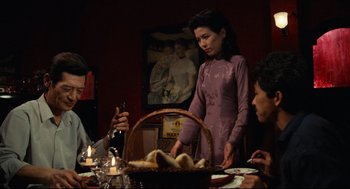 Movie still from “Boat People” (1982), directed by Ann Hui – A woman standing at a table with a basket of food; Medium shot, Over the shoulder angle