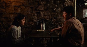 Movie still from “Boat People” (1982), directed by Ann Hui – A man and a woman sitting in front of a brick wall; Medium shot, High angle