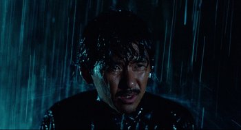 Movie still from “Boat People” (1982), directed by Ann Hui – A man in a black shirt is covered in water; Close Up shot, Low angle