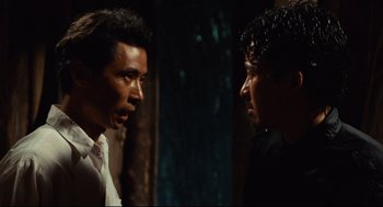 Movie still from “Boat People” (1982), directed by Ann Hui – Two men standing next to each other in the dark; Close Up shot, Over the shoulder angle