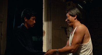 Movie still from “Boat People” (1982), directed by Ann Hui – Two men shaking hands in front of a building; Medium shot, Over the shoulder angle