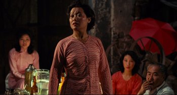 Movie still from “Boat People” (1982), directed by Ann Hui – A woman in a pink dress standing next to another woman in a red dress; Medium shot, Over the shoulder angle