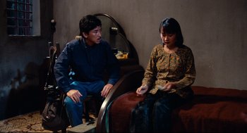 Movie still from “Boat People” (1982), directed by Ann Hui – A man and a woman sitting on a couch; Medium shot, High angle