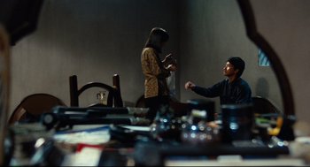 Movie still from “Boat People” (1982), directed by Ann Hui – A man and a woman are sitting at a dining room table; Wide shot, Over the shoulder angle