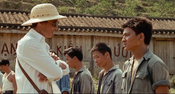 Movie still from “Boat People” (1982), directed by Ann Hui – A group of men standing next to each other in a field; Medium shot, Over the shoulder angle
