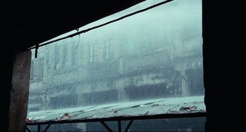 Movie still from “Boat People” (1982), directed by Ann Hui – A view from a train window of a building in the rain; Extreme Wide shot, Low angle