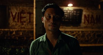 Movie still from “Boat People” (1982), directed by Ann Hui – A man in a green shirt is looking at the camera; Close Up shot, Over the shoulder angle