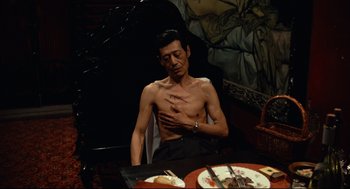 Movie still from “Boat People” (1982), directed by Ann Hui – A man sitting at a table with a plate of food in front of him; Medium shot, High angle