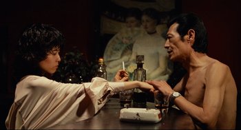 Movie still from “Boat People” (1982), directed by Ann Hui – Two people sitting at a table and one of them is holding a cigarette; Medium shot, Over the shoulder angle