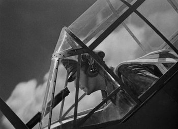 Movie still from “Bombardier” (1943), directed by Lambert Hillyer – An old photo of a man in a biplane; Medium shot, Low angle
