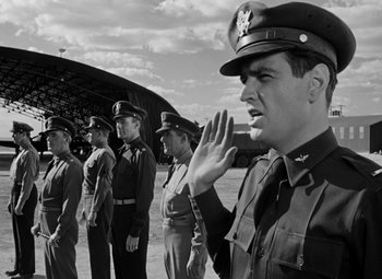 Movie still from “Bombardier” (1943), directed by Lambert Hillyer – Black and white photograph of military men saluting; Medium shot, Low angle