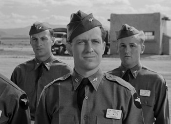 Movie still from “Bombardier” (1943), directed by Lambert Hillyer – A black and white photo of a group of men in uniform; Medium shot, Low angle