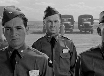 Movie still from “Bombardier” (1943), directed by Lambert Hillyer – A black and white photo of a group of men in uniform; Medium shot, Low angle